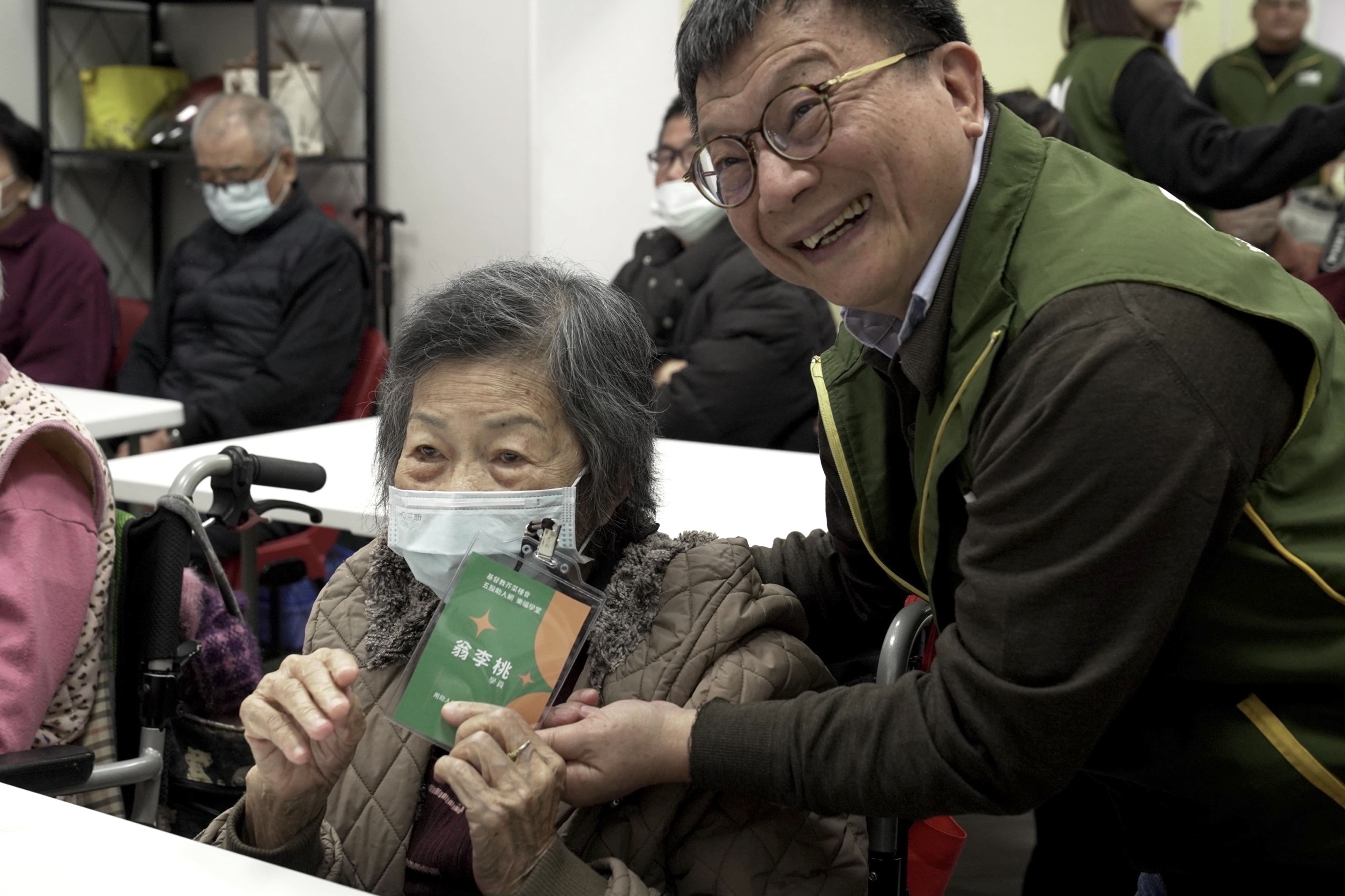 《圖說》芥菜種會執行長李肇家(右一)為五股助人網「樂福學堂」長者們掛學生證,給予愛的鼓勵。〈芥菜種會提供〉