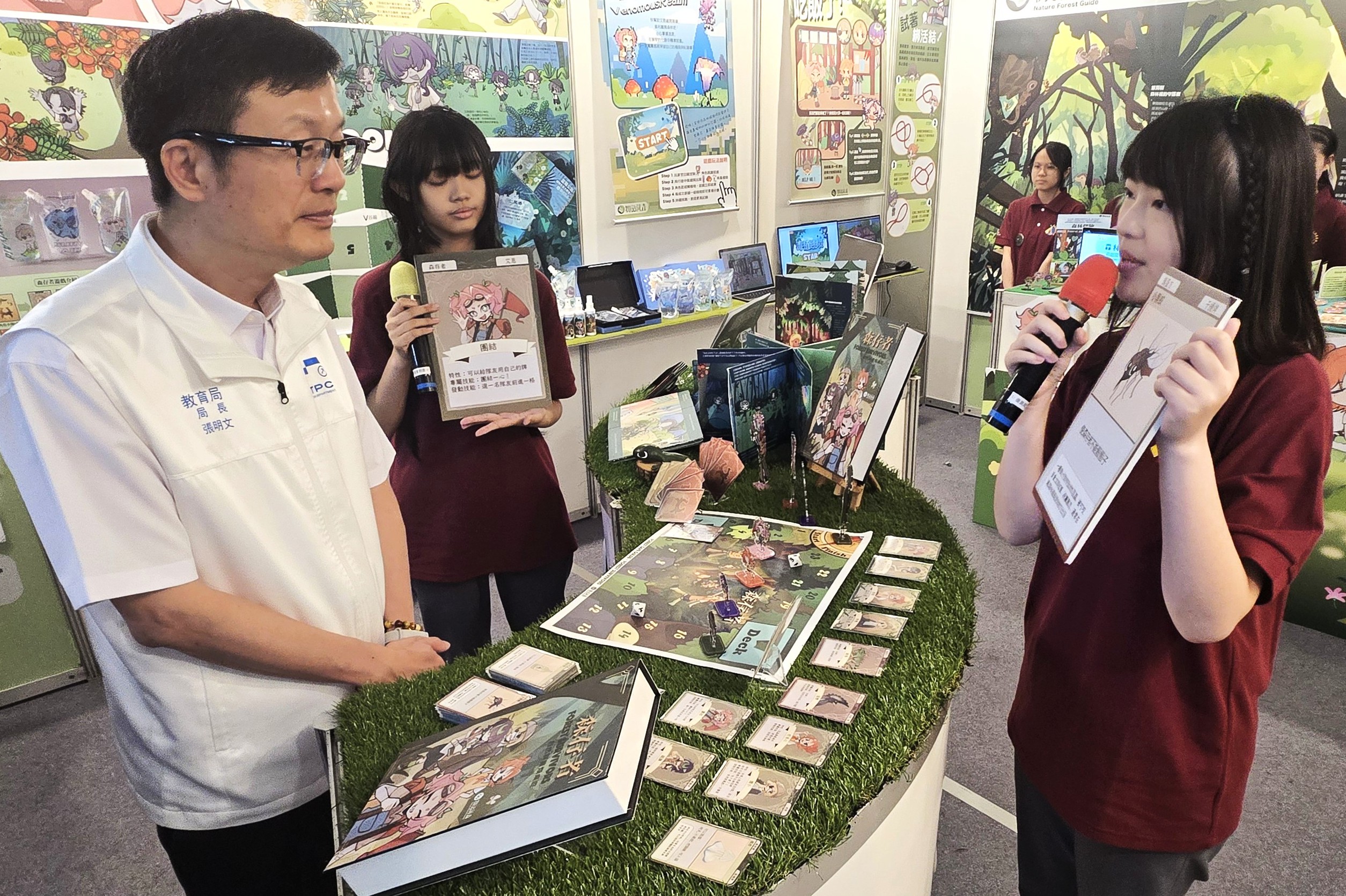《圖說》廣告設計科陳沛綺及王怡涵同學向張明文局長介紹115年專題實作競賽創意組第一名作品「物語藏。〈教育局提供〉